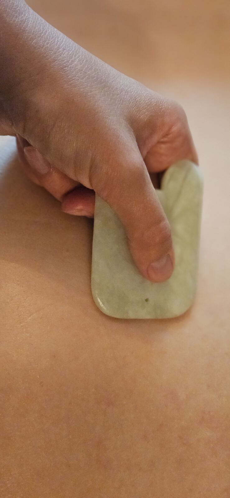 Gua sha met een jadesteen op de huid